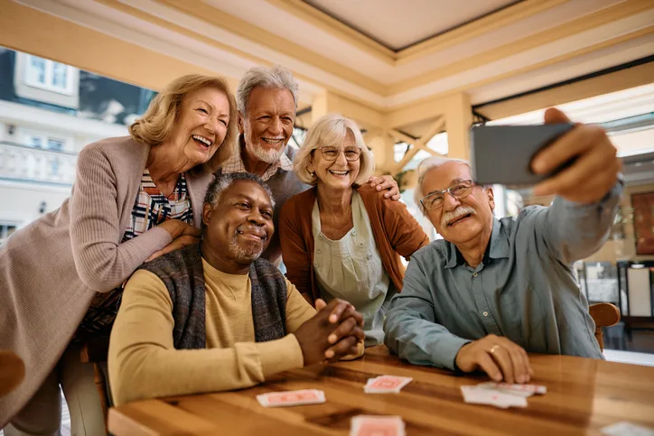 Groupe multiracial de personnes âgées heureuses prenant un selfie avec leur téléphone portable dans une maison de retraite.
